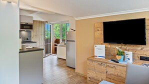 A modern kitchen with a built-in oven, a refrigerator, and a dining area with a table and chairs.