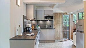 A modern kitchen with a central island, built-in appliances, and a sliding glass door leading to a deck.