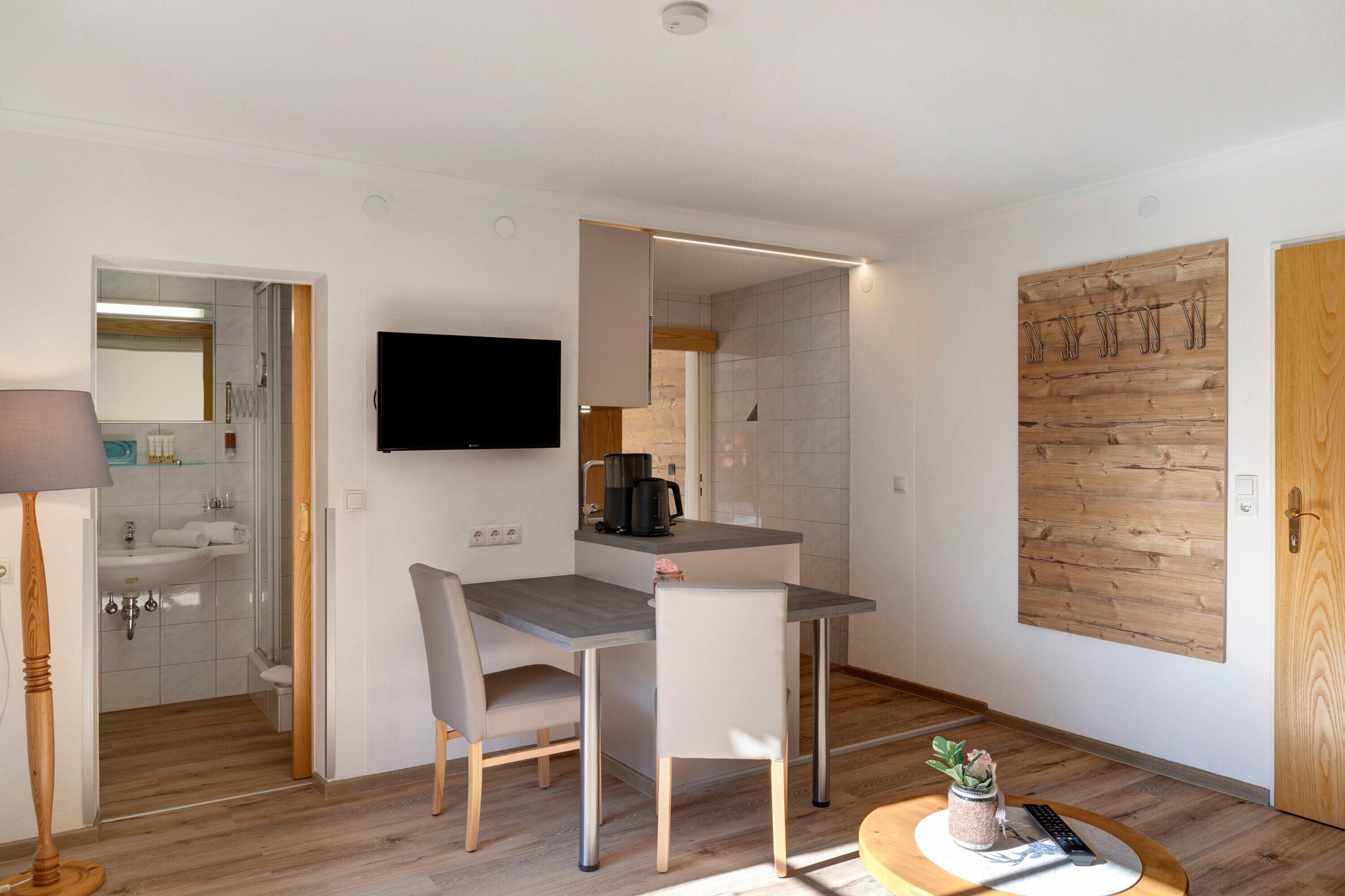 Una cocina moderna con una mesa de comedor, sillas, un televisor y una puerta de madera.