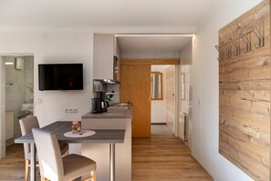 A modern kitchen with a flat-screen TV, a coffee maker, and a wooden wall with hooks. - Apartment 'Top 5' with Mountain View, Balcony and Wi-Fi (Oetz)