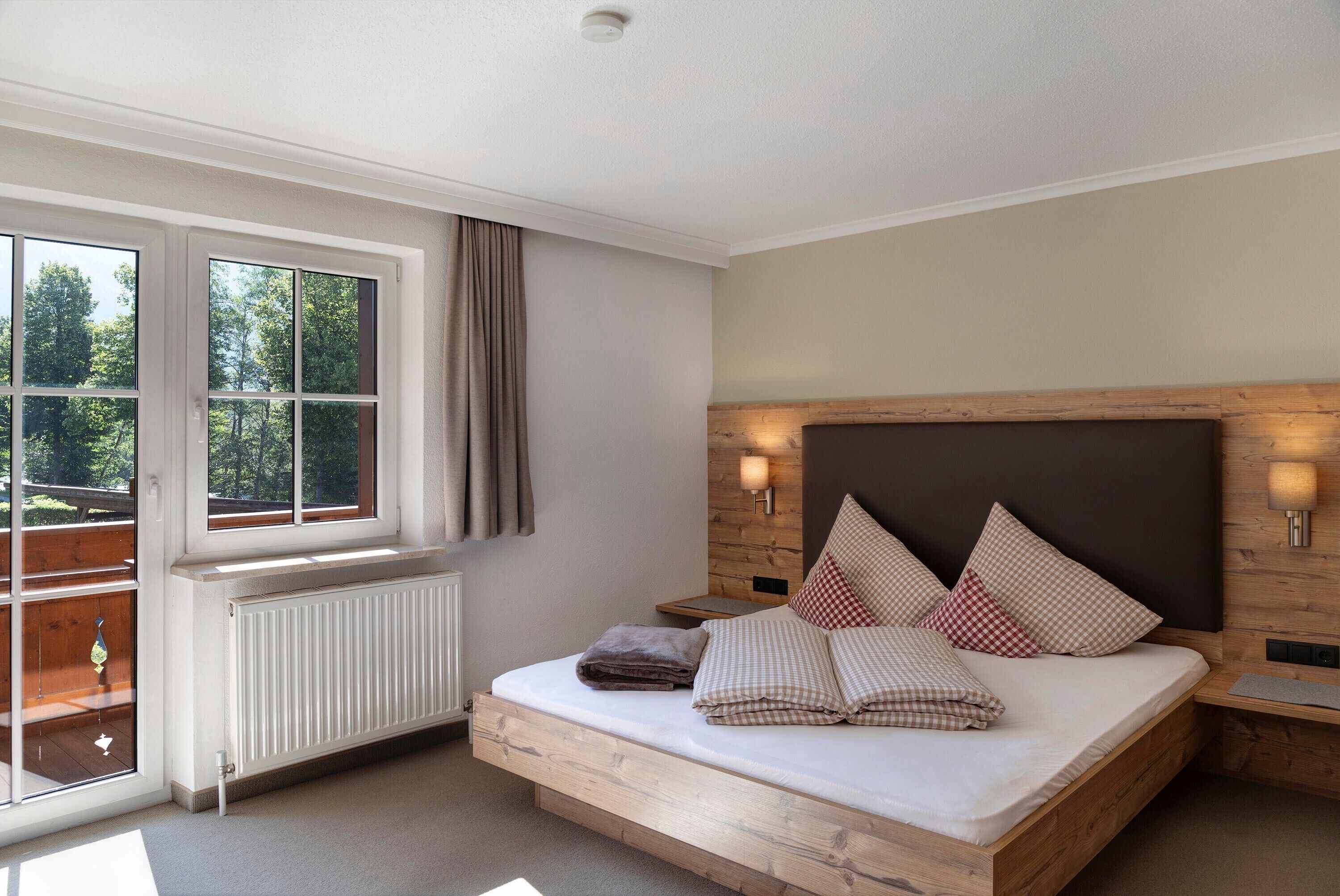 Une chambre à coucher avec un lit, une fenêtre, un radiateur et une table de chevet avec une lampe.