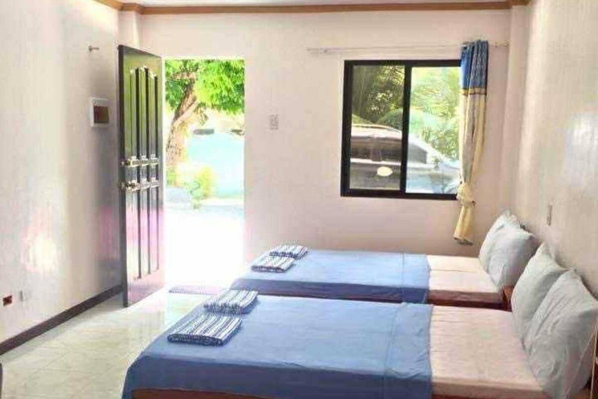 A room with two beds, a window, and a door leading outside.