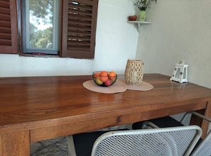 A wooden table with a woven mat, a bowl of fruit, a woven vase, and a small white lantern. - Holiday Home Viki (Korčula)