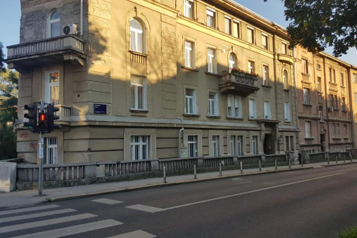 Ein mehrgeschossiges Gebäude mit Balkon, einer Ampel und einer Fußgängerüberweg.