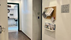 Käytävä, jossa on puulattia, numero ’10’ -kyltti ja ilmoitustaulu, jossa on painettuja materiaaleja.