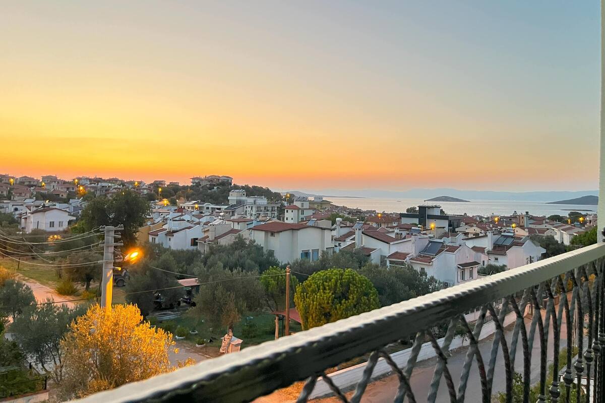 A residential area with houses, a clear sky, and a distant view of the sea.