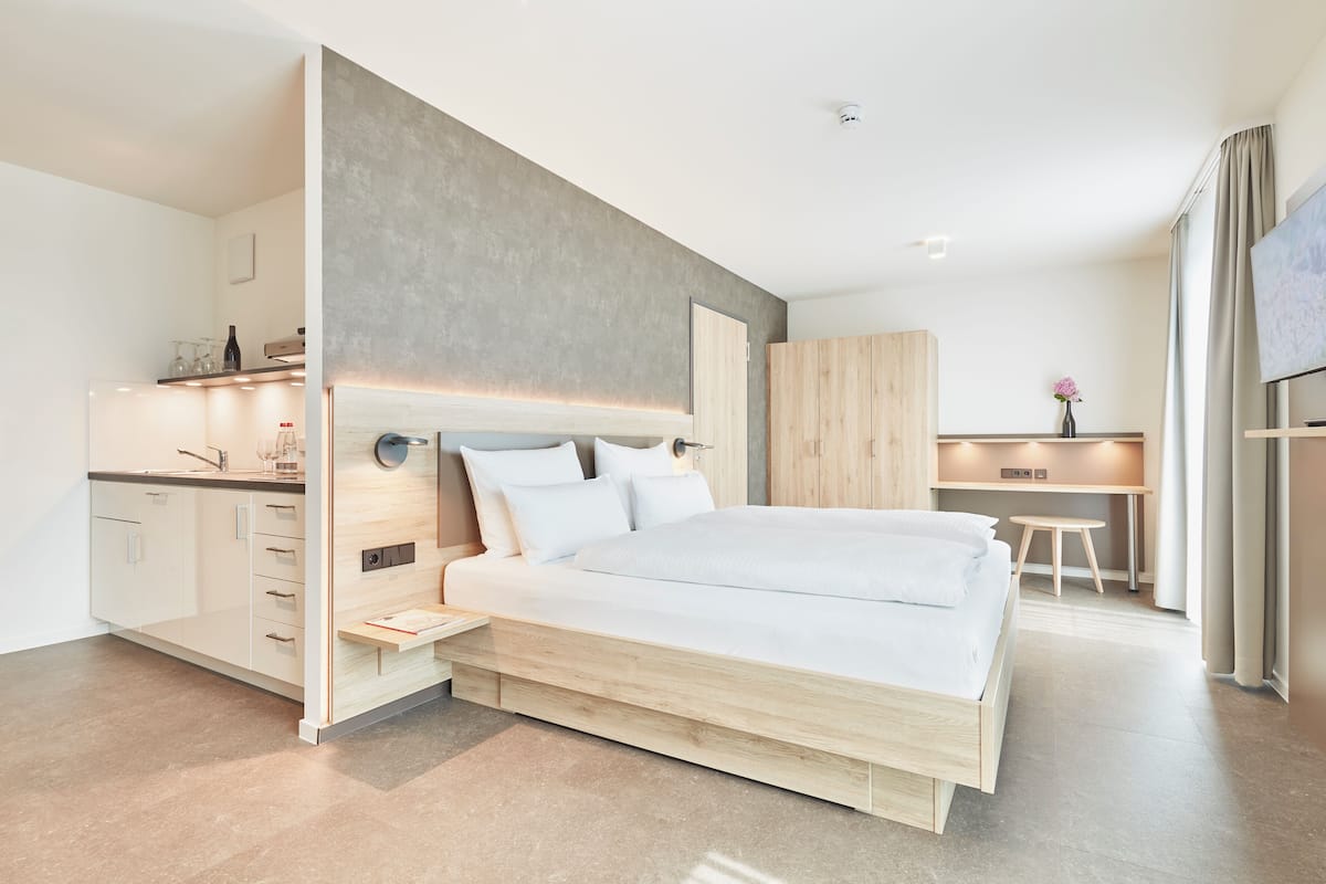 A modern bedroom with a bed, bedside tables, a desk, and a wardrobe.
