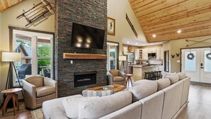 A modern living room with a stone fireplace, a large flat-screen TV, and a cozy sectional sofa.