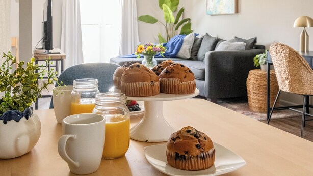 Ett matbord med muffins, en kaffekopp och ett glas apelsinjuice.