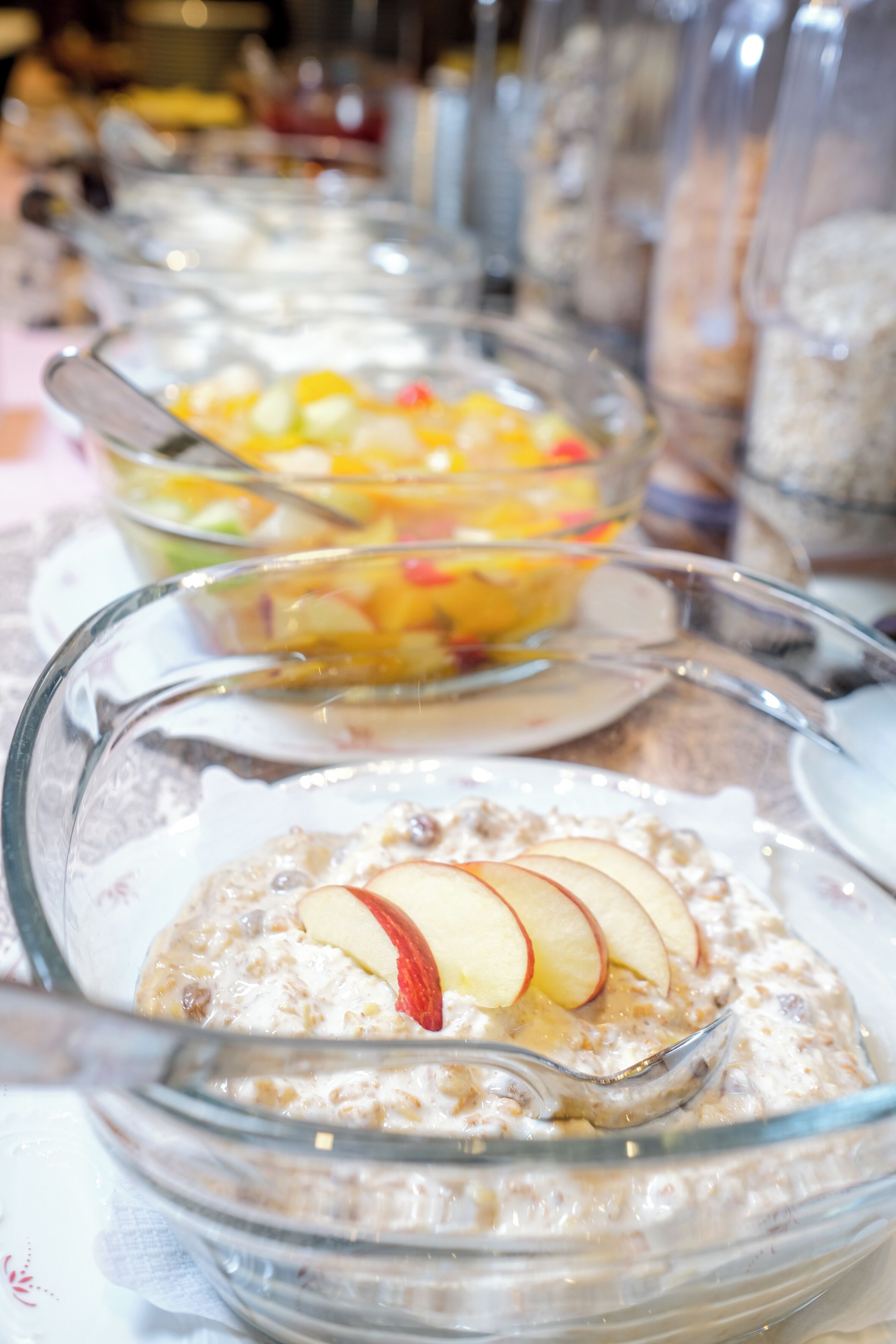Un buffet proposant divers plats, notamment un bol de porridge garni de tranches de pommes et un saladier de salade de fruits.