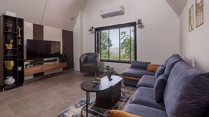 Uma sala de estar moderna com televisão de tela plana, um sofá, uma poltrona e uma mesa de centro.