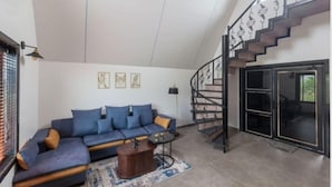 Uma sala de estar moderna com um sofá seccional, uma mesa de centro e uma escada com corrimão de metal.