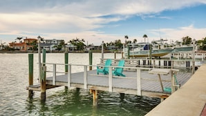 A wooden dock with turquoise chairs, a boat, and a marina with buildings in the background. - Ocean View, Pool & Boat Dock: Indian Rocks Retreat (Indian Rocks Beach)