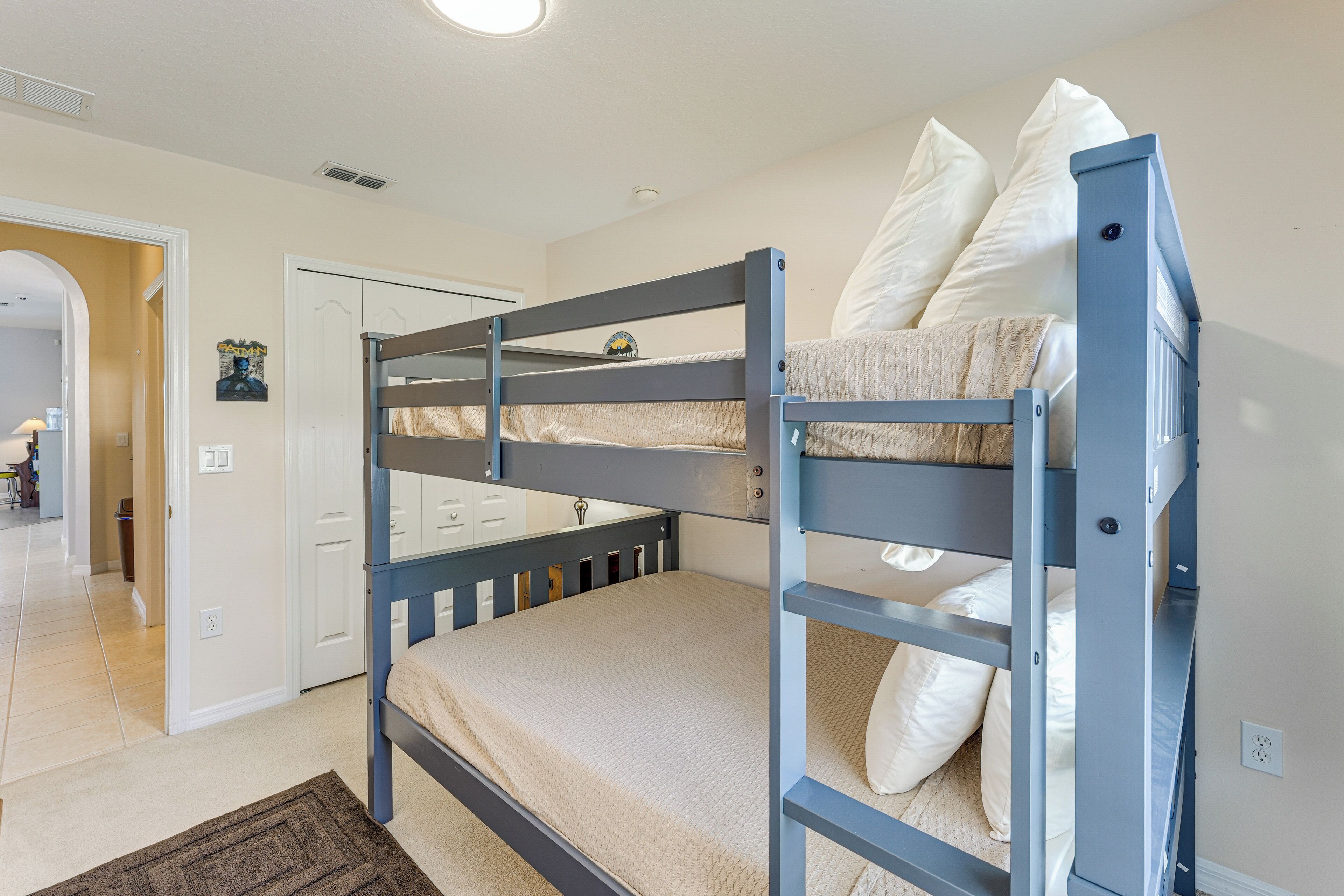 A bunk bed with a lower bunk and a headboard, a white door, and a small picture on the wall.