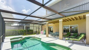 A covered swimming pool with lounge chairs, a patio area, and a view of the backyard. - Pool, Games + Family Fun! Davenport Home by Disney (Davenport)