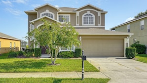A two-story house with a garage, a well-maintained lawn, and a mailbox in the driveway. - Pool, Games + Family Fun! Davenport Home by Disney (Davenport)