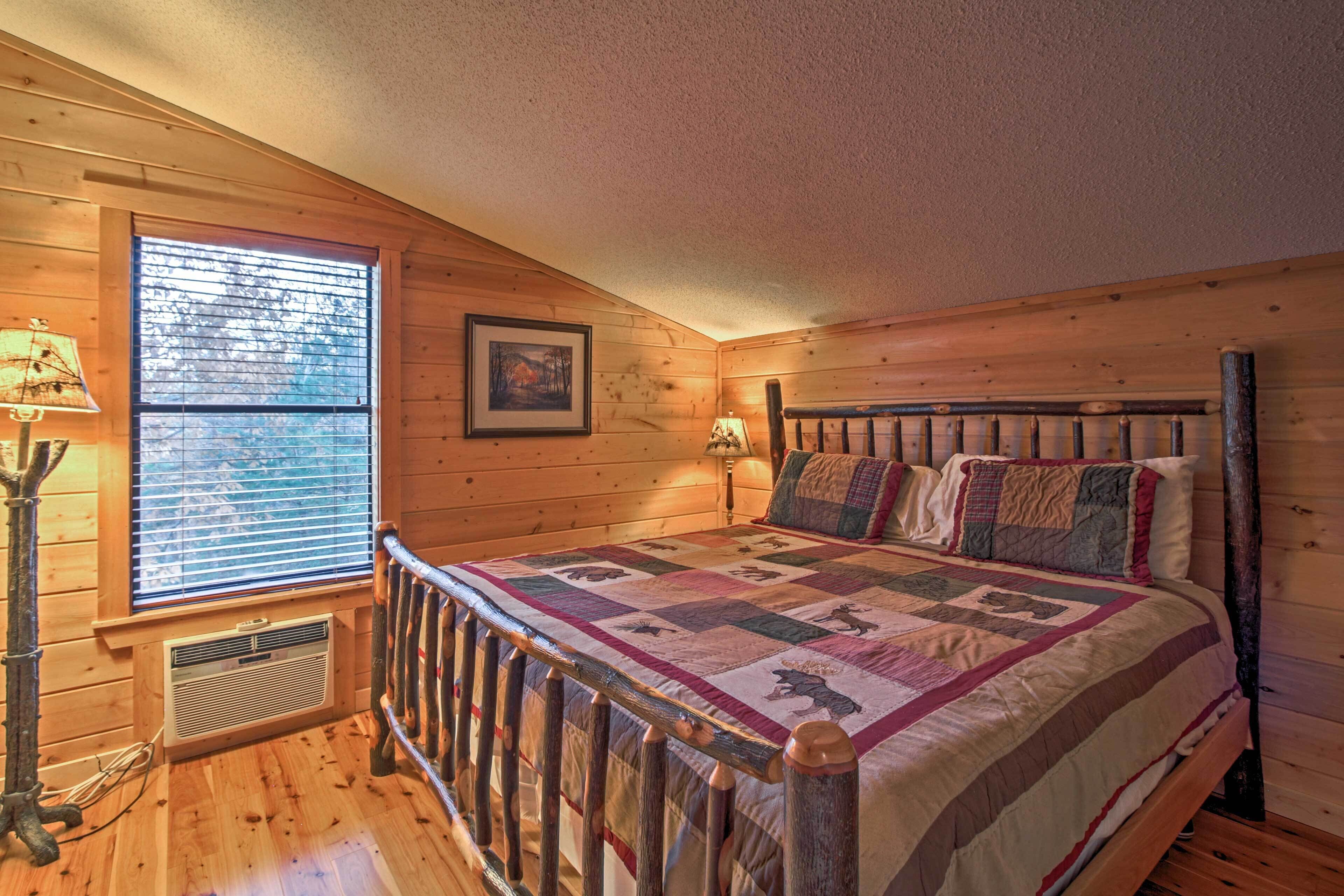 A cozy bedroom with a wooden bed, a window with blinds, a framed picture on the wall, and a nightstand with a lamp.