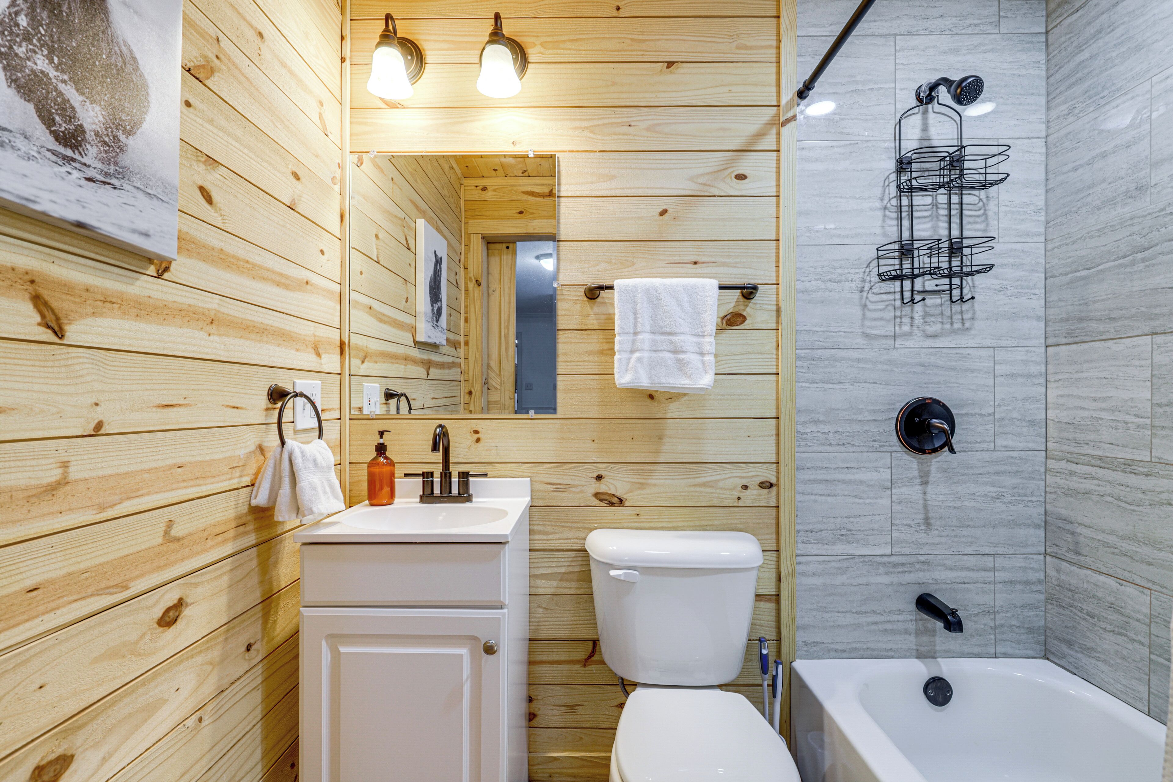 Ein Badezimmer mit Holzwandverkleidung, Waschbecken, Toilette und Badewanne.