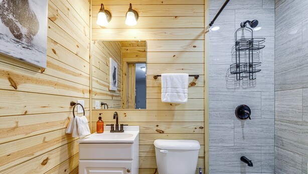 A wooden-paneled bathroom with a sink, toilet, and bathtub. - Pet-friendly Gatlinburg Cabin w/ Hot Tub! (Gatlinburg)