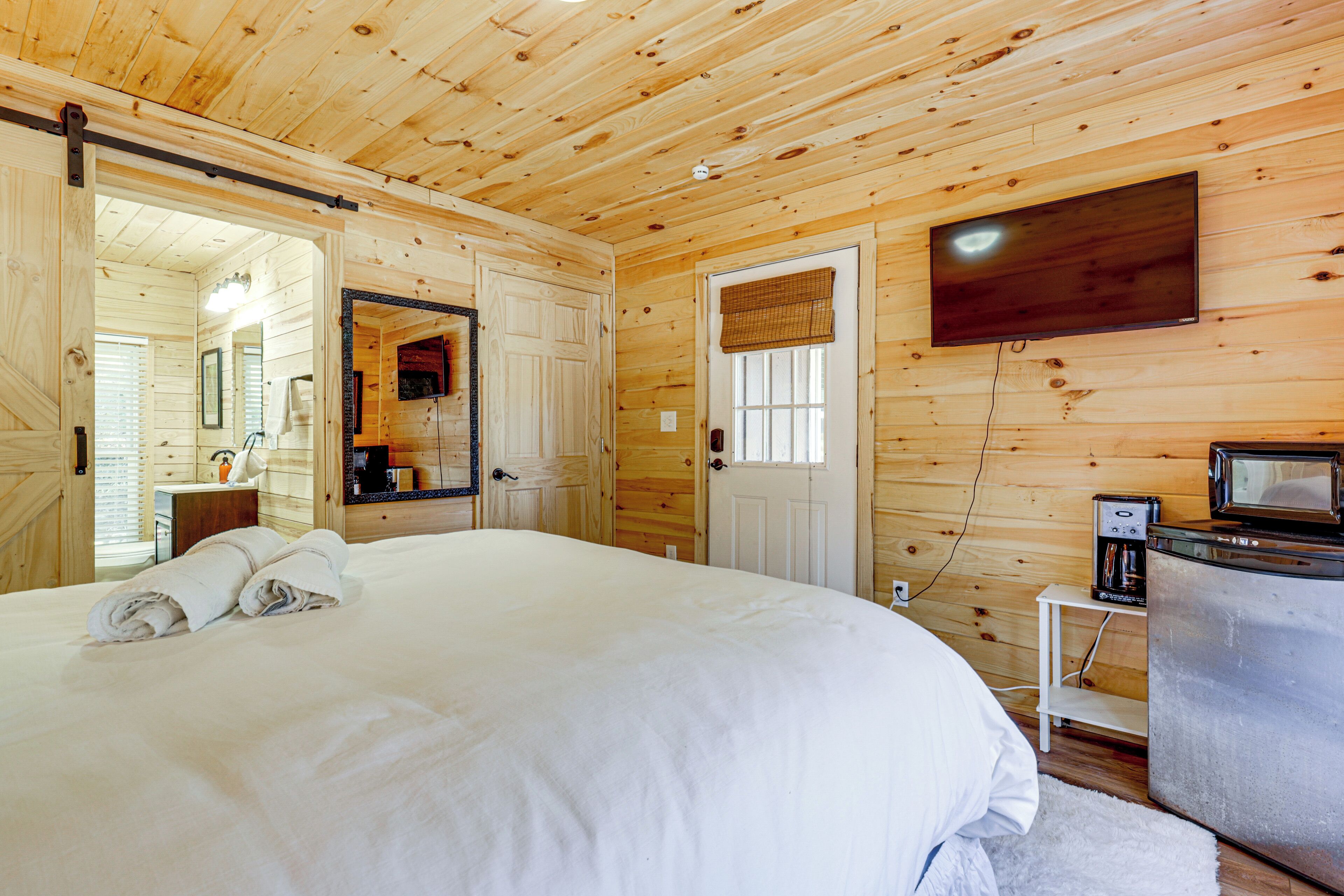 A wooden-paneled bedroom with a large bed, a television, and a microwave.