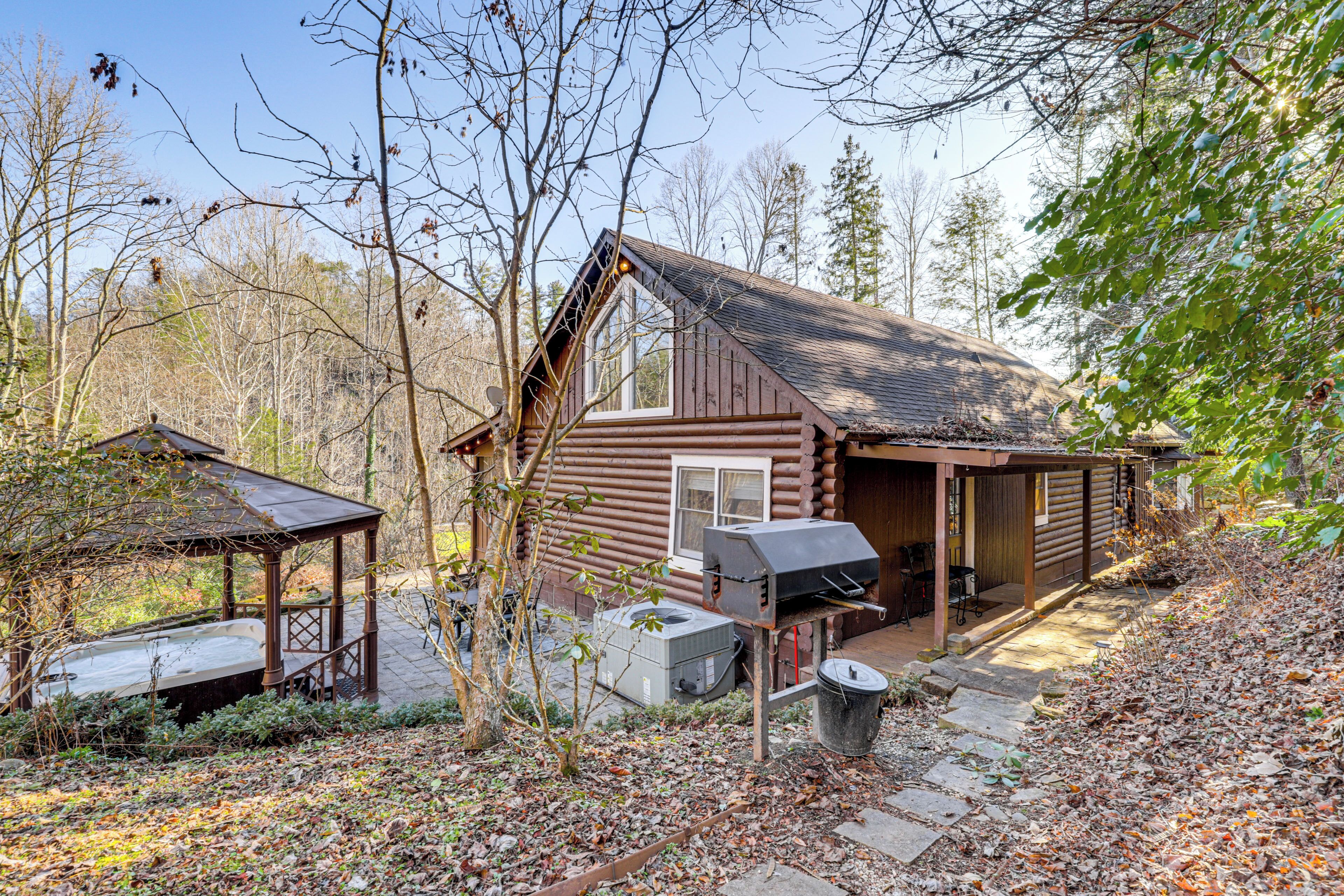 A rustic cabin with a chimney, a covered porch, and a hot tub.