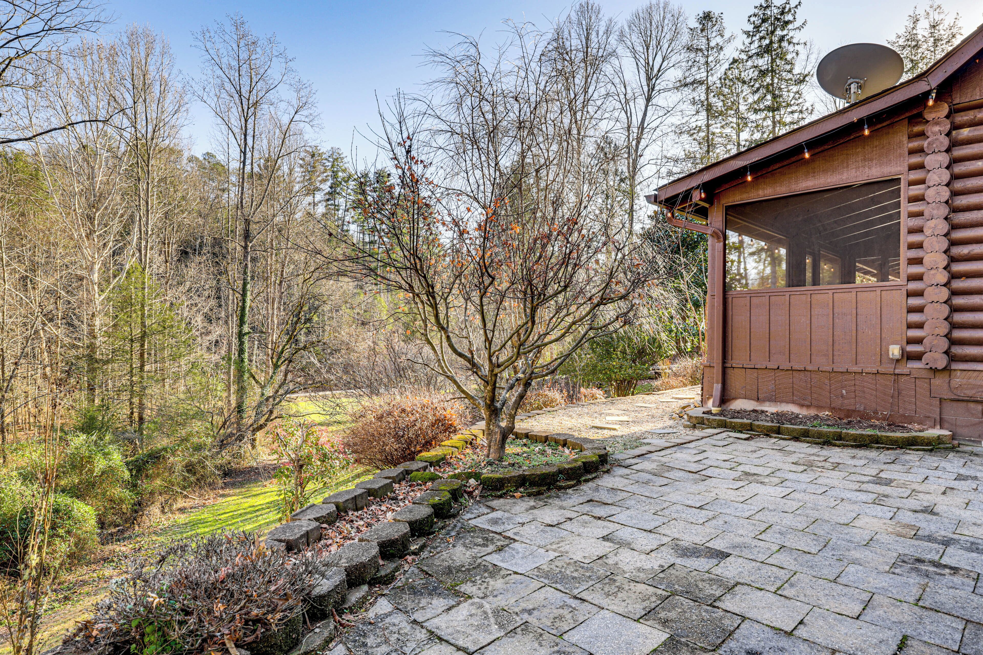A rustic cabin with a stone-paved entrance, surrounded by a forested area.