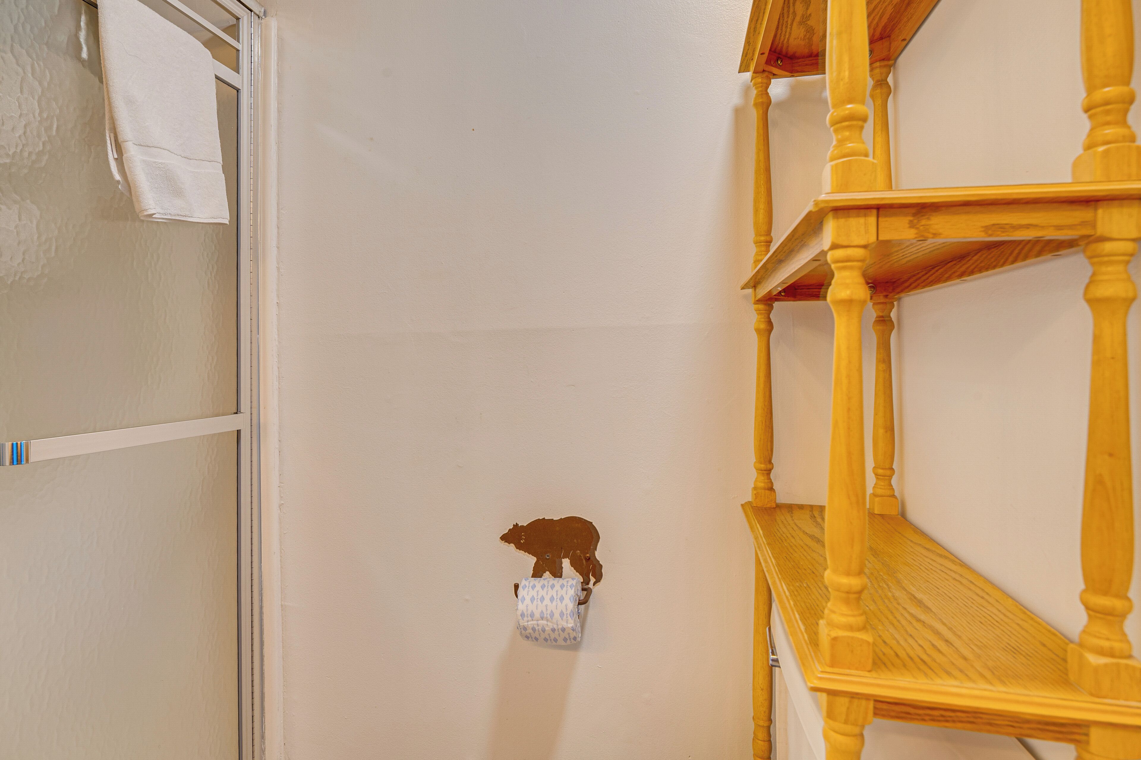 Een badkamer met een handdoekhouder, een houten plank en een wandbevestigde zeepdispenser.