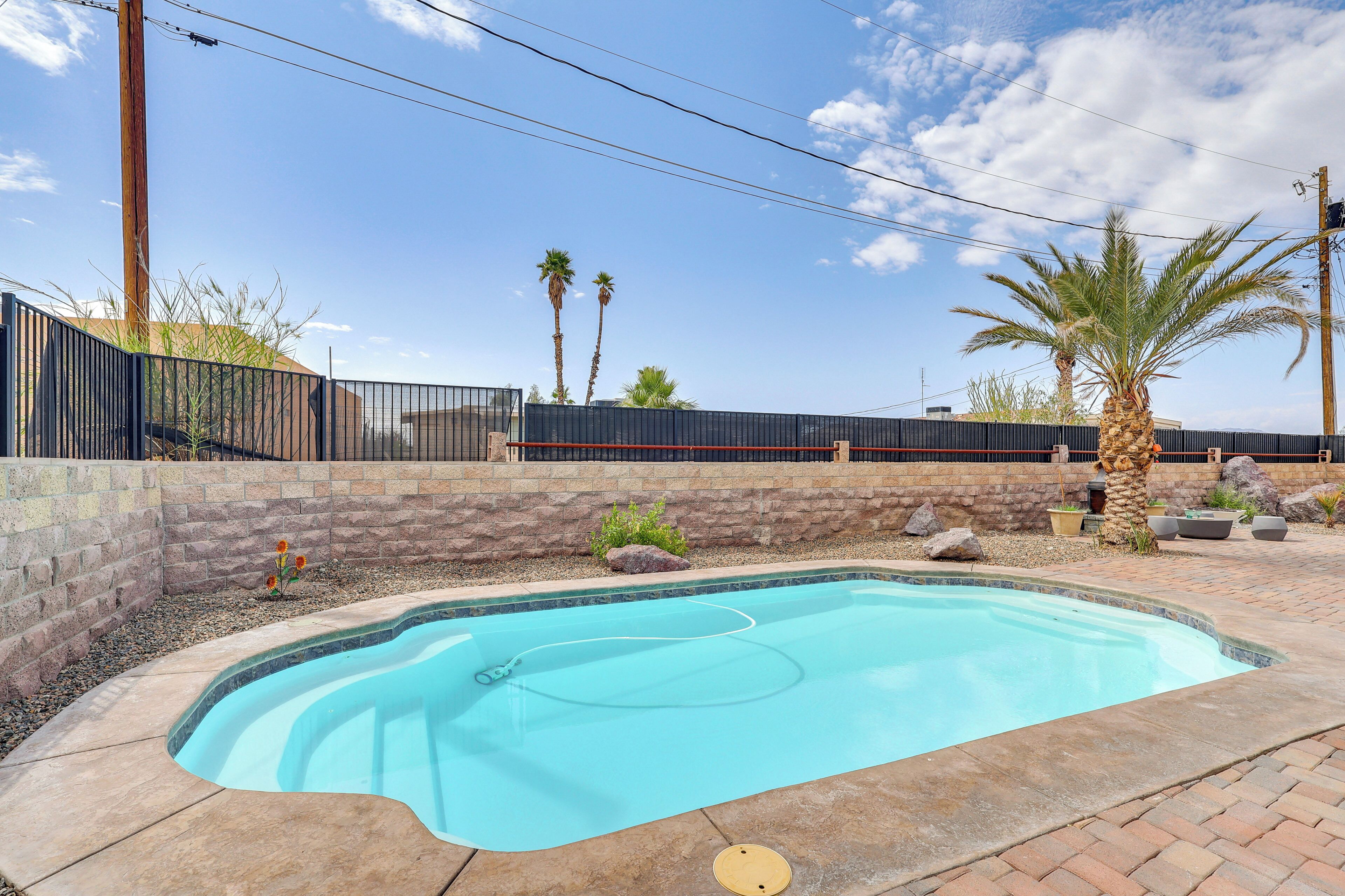A swimming pool with a curved edge, surrounded by a brick wall and a metal fence.