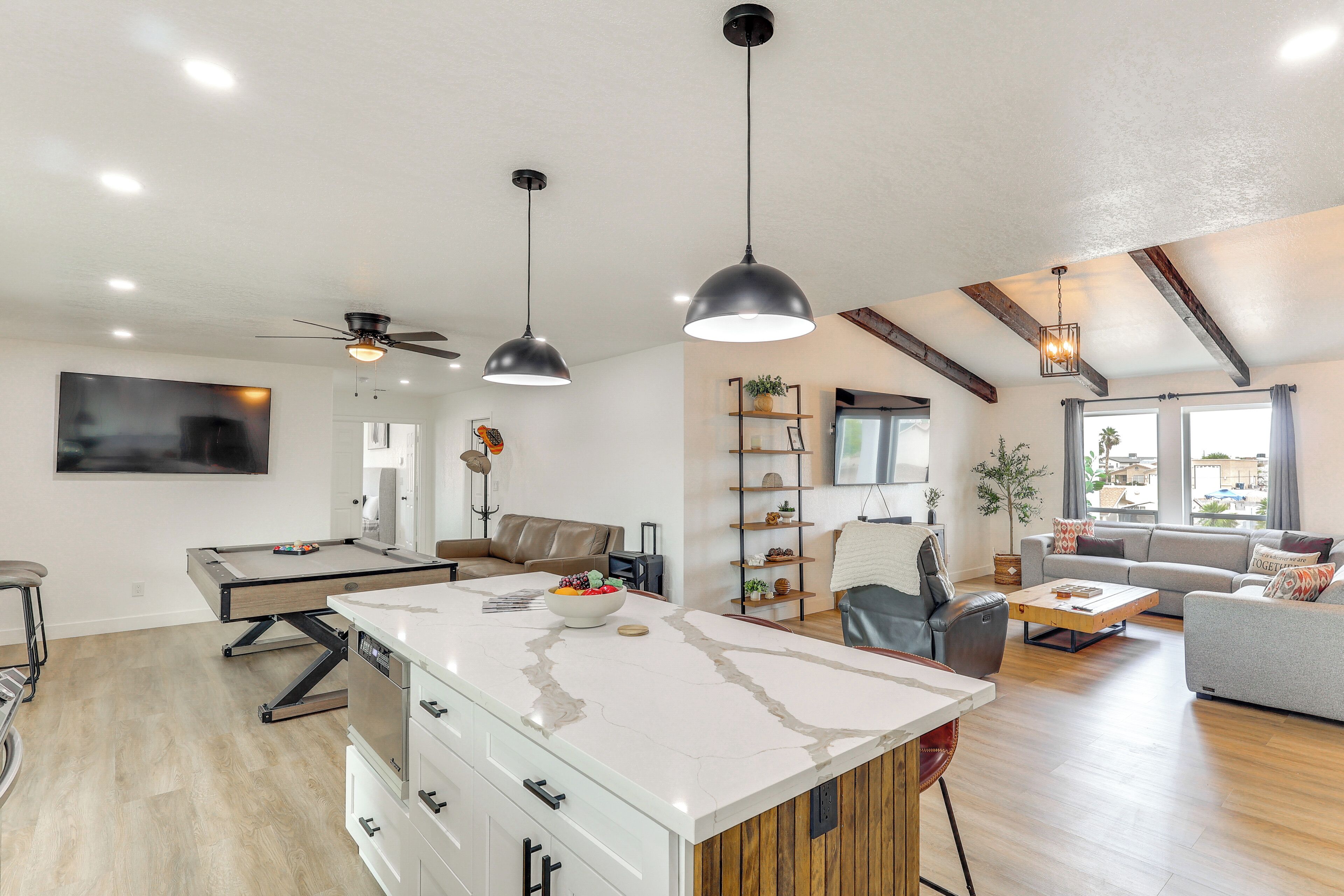 Une cuisine moderne dotée d’un îlot central, de luminaires suspendus et d’un ventilateur de plafond.