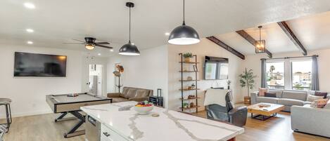 Une cuisine moderne dotée d’un îlot central, de luminaires suspendus et d’un ventilateur de plafond.