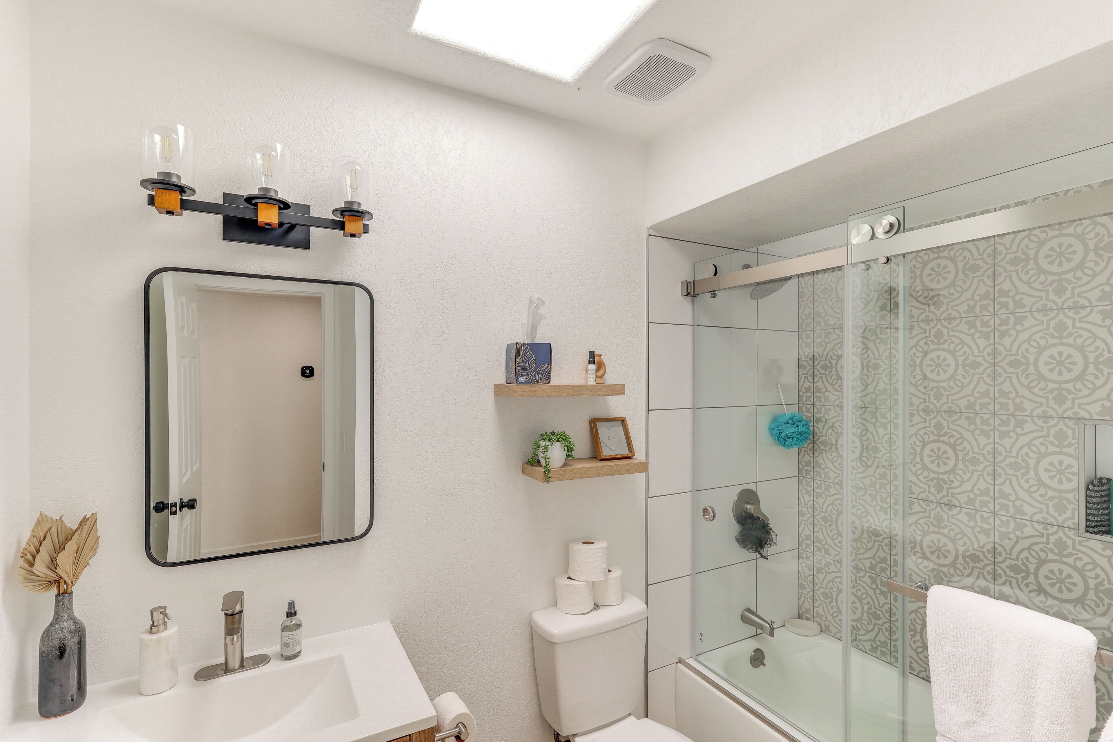 A modern bathroom with a glass shower, a white sink, a mirror, and a toilet.