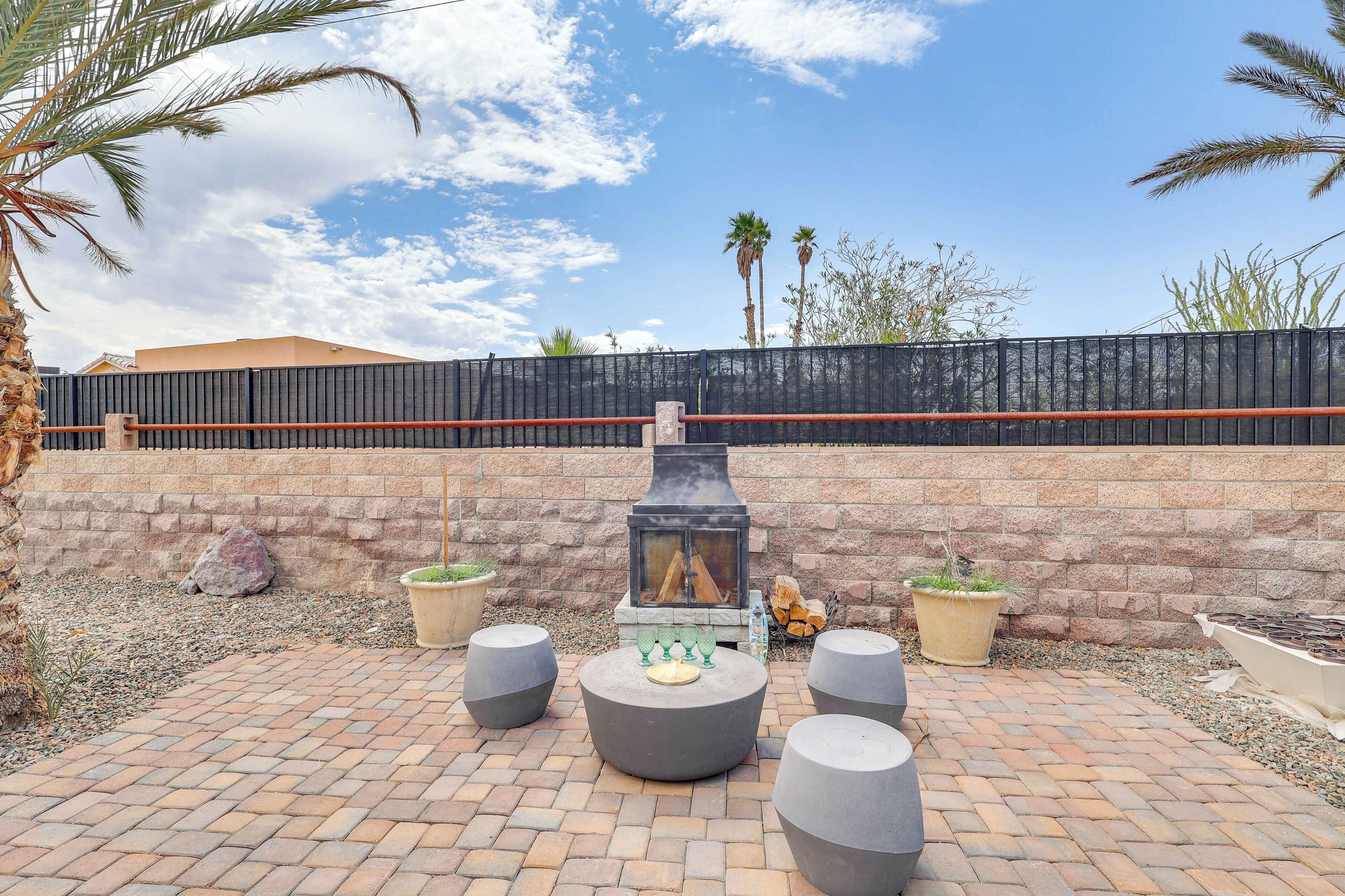 An outdoor patio with a stone fireplace, seating areas, and a brick pathway.