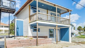 En tvåvåningsbyggnad med en balkong, ett garage och en liten veranda.
