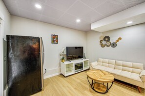 A modern living room with a flat-screen TV, a white sofa, a wooden coffee table, and a glass-fronted entertainment unit. - 2 Mi to Des Moines Beach Park: Mod Des Moines Apt (Des Moines)