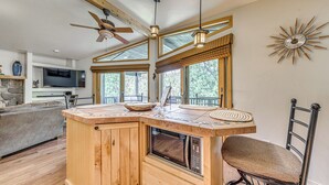 Una cocina con isla de madera, microondas integrado y ventilador de techo.