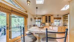 Una cocina amplia con una isla central, armarios de madera y un ventanal con vistas a una terraza.