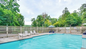 A swimming pool with lounge chairs and a fence. - Private Hot Tub: Lake Resort Cabin in Sevierville! (Sevierville)