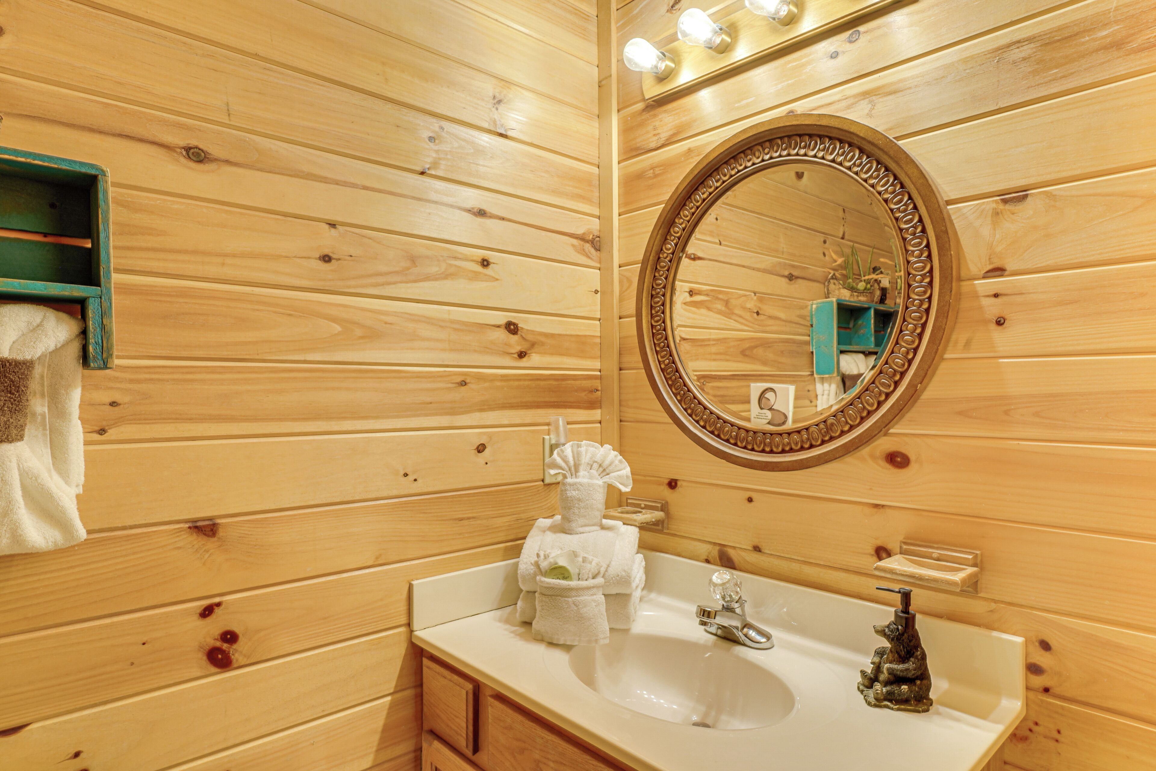 A wooden-paneled bathroom with a sink, mirror, and towel rack.