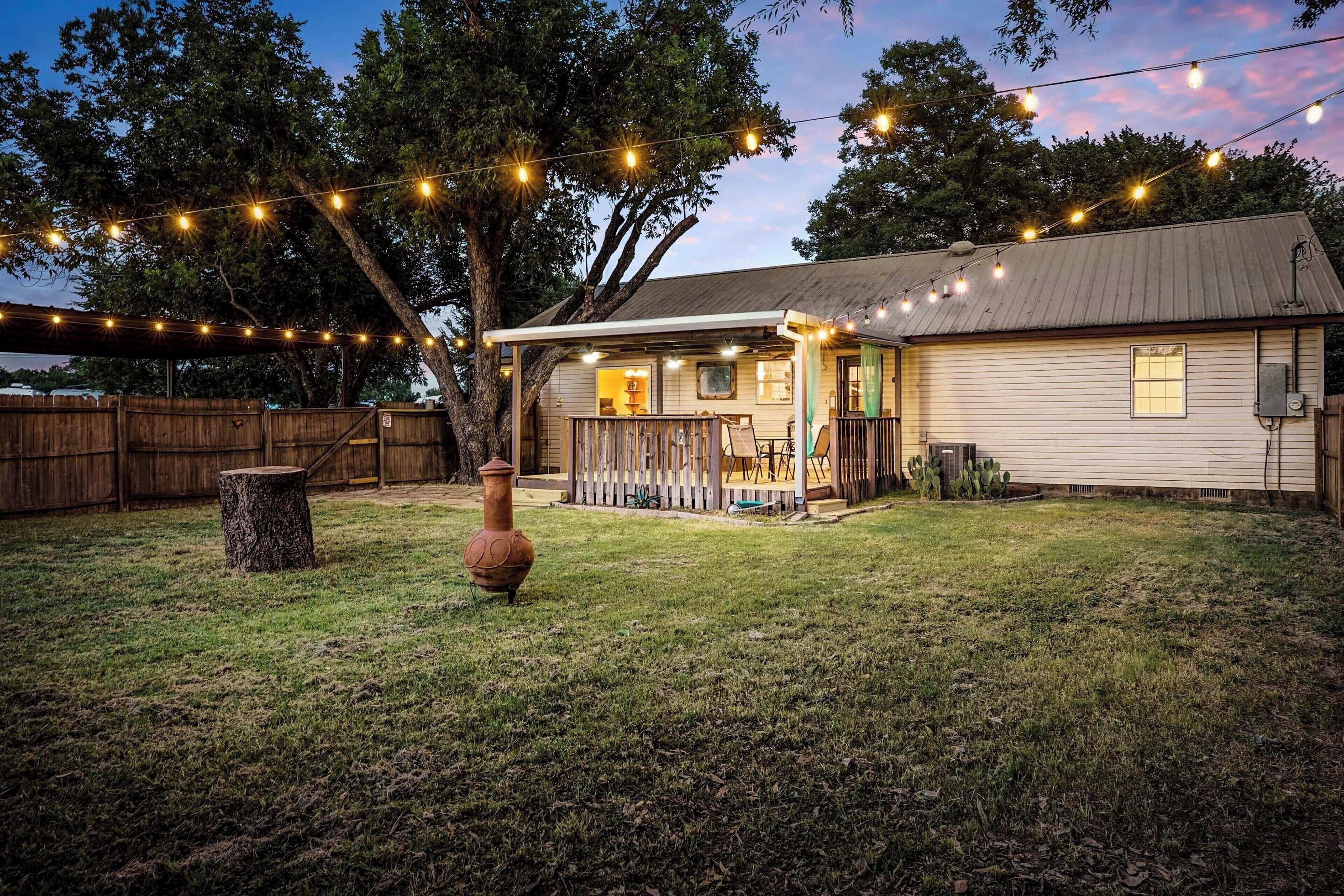 A house with a porch, a wooden fence, and string lights.