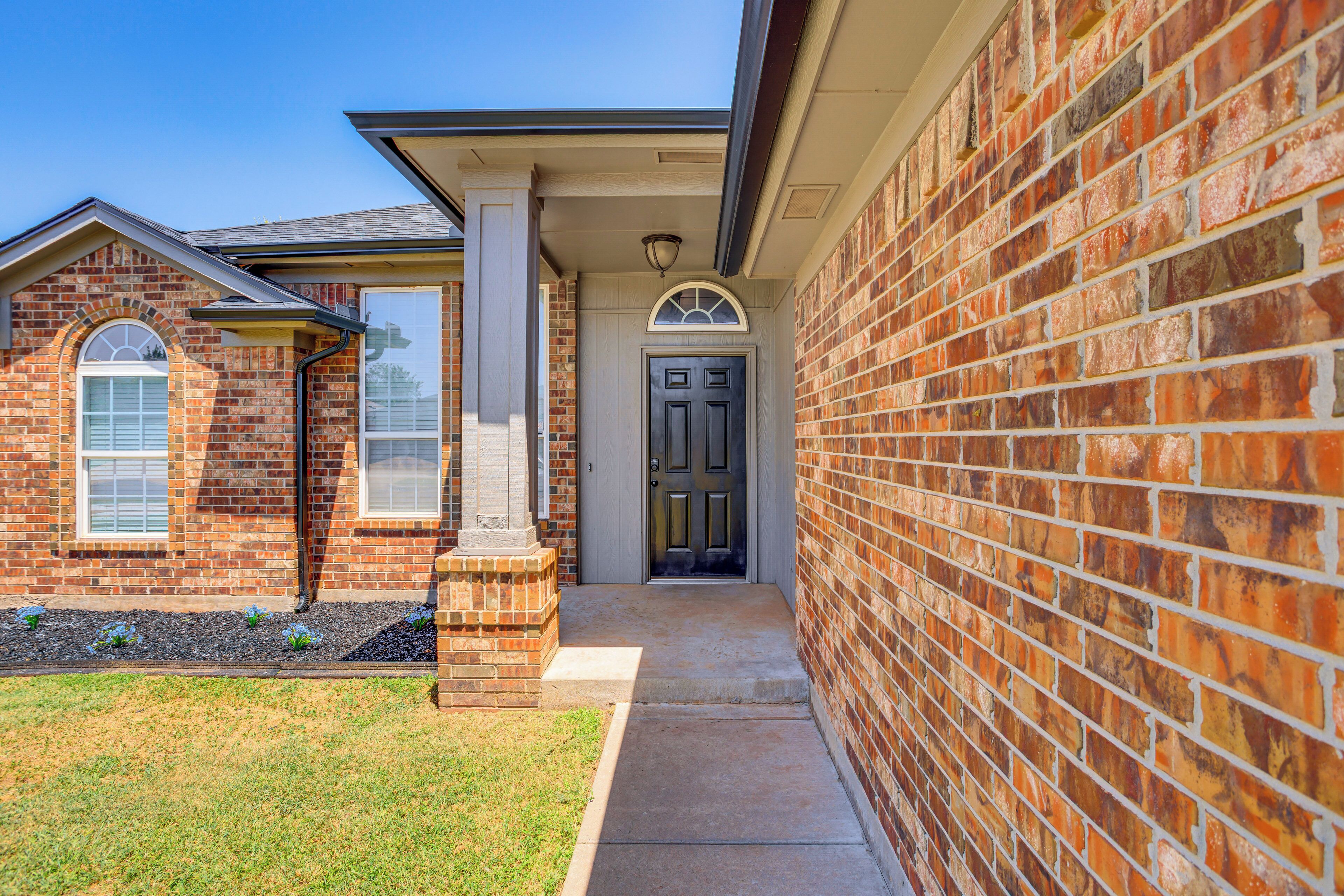 A brick house with a front door, a small porch, and a window.