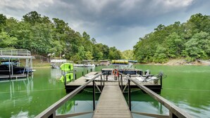 A wooden dock leading to a boat dock with several boats and a canopy.