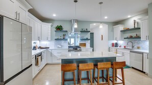 A modern kitchen with white cabinets, a central island with bar stools, and pendant lighting. - Serene 1/3 Acre-families, Exec, Mayo (Pine Island)