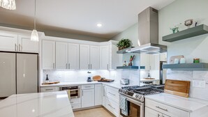 A modern kitchen with white cabinetry, a central island, a stove, and a built-in oven. - Serene 1/3 Acre-families, Exec, Mayo (Pine Island)