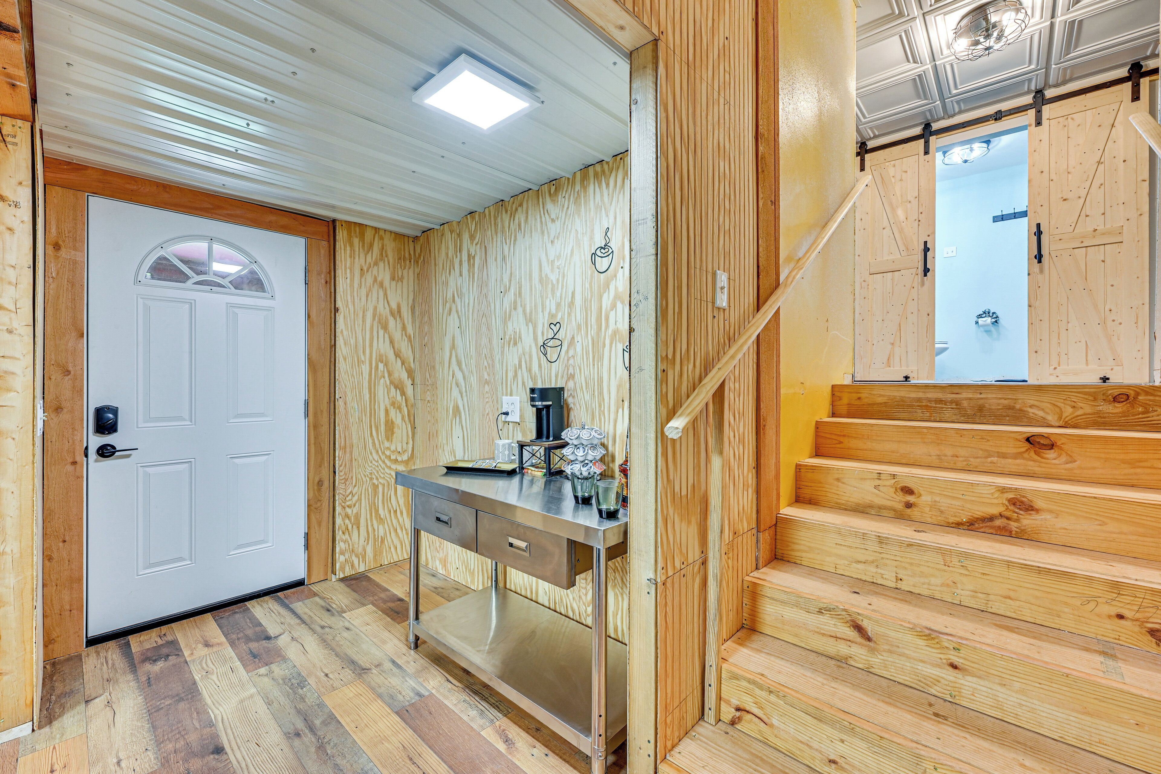 A wooden interior with a white door, a desk with drawers, and a staircase.