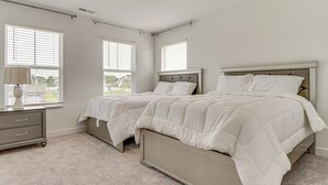 Un dormitorio con dos camas, un tocador y una ventana con persianas.