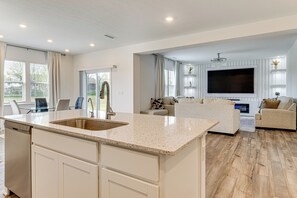 A modern kitchen with a large island, a dining area with glass tables, and a living room with a TV and sofas. - 16 Mi to Indianapolis: Group Getaway w/ Pool Table (Avon)