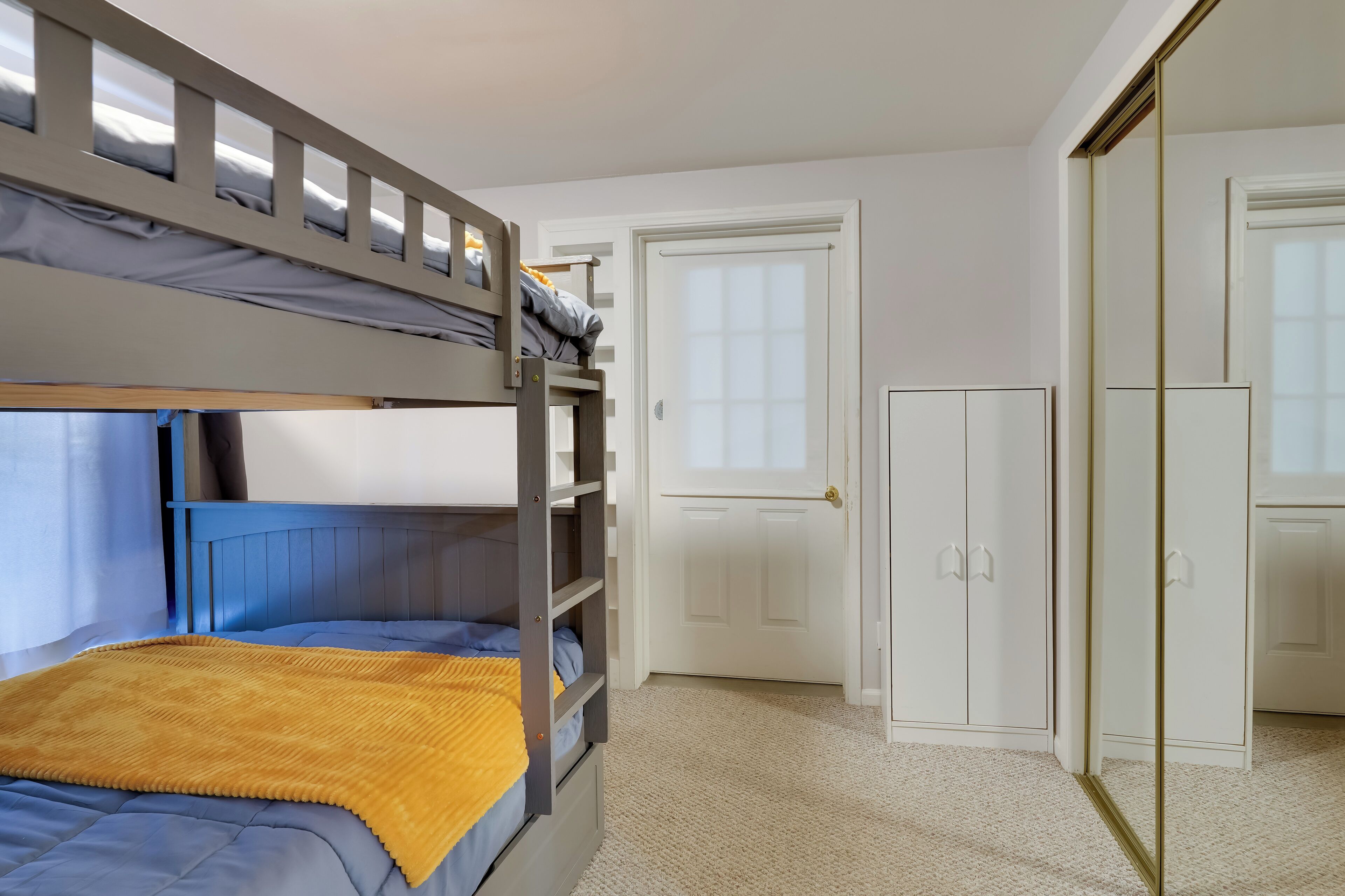 A bunk bed room with a wardrobe and a door.
