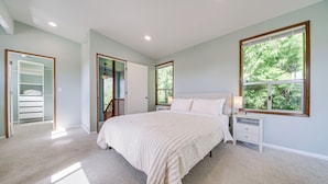 A bedroom with a large bed, a nightstand, a window with a view of trees, and a closet with a mirror. - < 1 Mi to Lake Washington: Peaceful Apt in Kenmore (Kenmore)