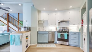 A modern kitchen with white cabinets, a microwave, a dishwasher, and a stove. There is a wooden staircase leading to another room. - < 1 Mi to Lake Washington: Peaceful Apt in Kenmore (Kenmore)