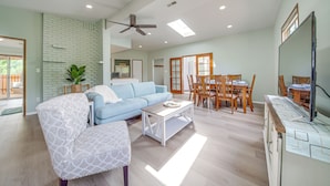 A spacious living room with a blue sofa, a white armchair, a wooden coffee table, and a dining area with wooden chairs and a table. - < 1 Mi to Lake Washington: Peaceful Apt in Kenmore (Kenmore)